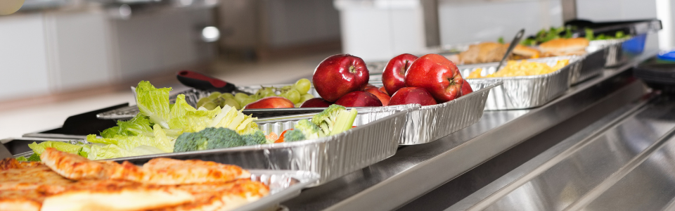 Cafeteria line with food in trays.
